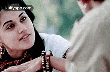 A Woman Is Putting A Bracelet On A Man 'S Wrist And Smiling . GIF