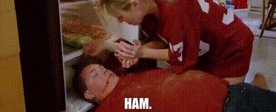 A Woman Is Putting Ham In A Man 'S Mouth . GIF