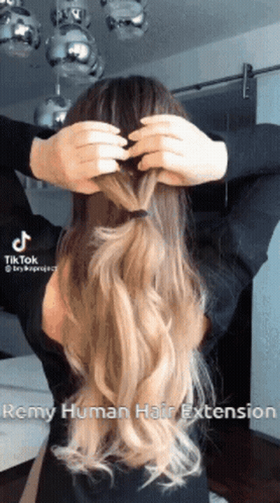A Woman Is Putting Her Hair In A Braid . GIF