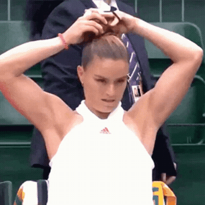 A Woman Is Putting Her Hair In A Bun While A Man In A Suit Is Standing Behind Her . GIF