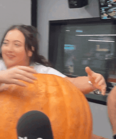 A Woman Is Putting Her Hand On A Pumpkin That Says ' T.v. ' On It GIF