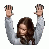 A Woman Is Raising Her Hands In The Air And Looking Down . GIF