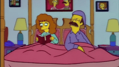 A Woman Is Reading A Book To A Man Who Is Sleeping In A Bed . GIF