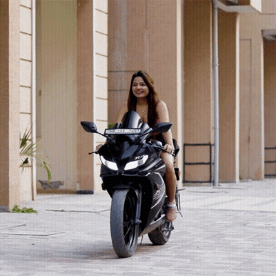 A Woman Is Riding A Black Motorcycle With A License Plate That Says ' Jc ' On The Front GIF