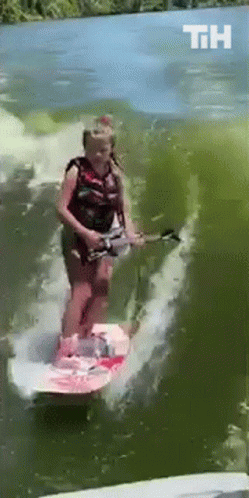 A Woman Is Riding A Surfboard In The Water And The Letters Th Are Visible GIF