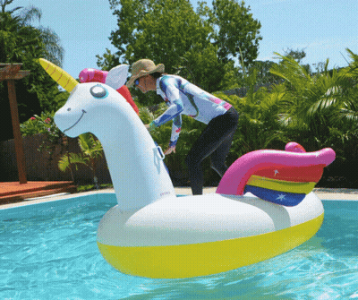 A Woman Is Riding On An Inflatable Unicorn In A Swimming Pool GIF