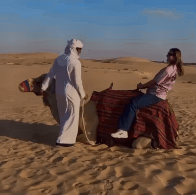 A Woman Is Riding On The Back Of A Camel GIF