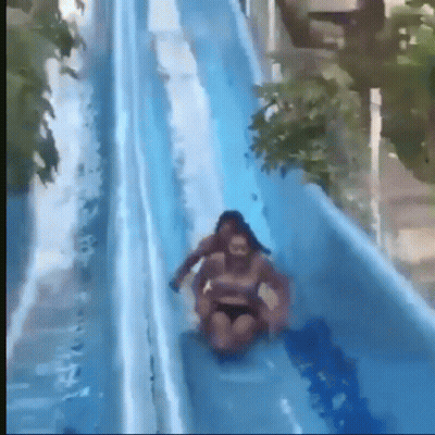 A Woman Is Riding On The Back Of A Man On A Water Slide GIF