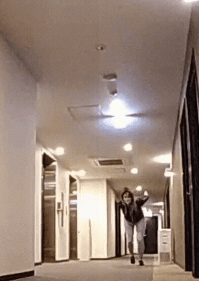 A Woman Is Running Down A Hallway In A Building . GIF