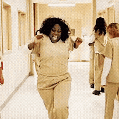 A Woman Is Running Down A Hallway In A Hospital While A Group Of Women Are Standing Behind Her . GIF