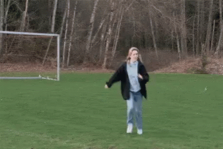 A Woman Is Running In A Field With A Man In A Red Sweater Behind Her . GIF