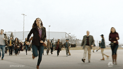 A Woman Is Running In Front Of A Crowd With The Hashtag #Manifest On The Bottom GIF
