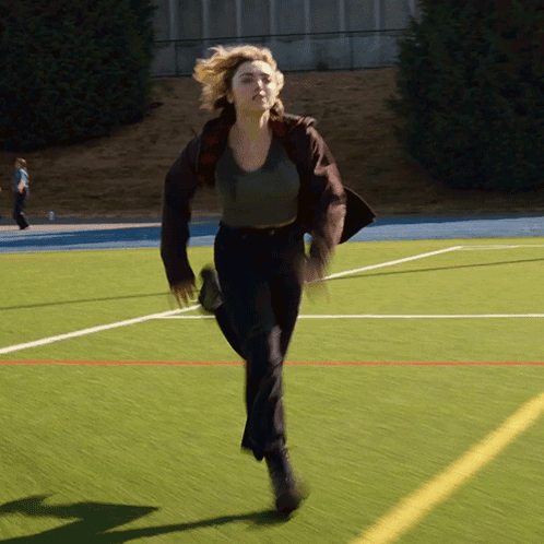 A Woman Is Running On A Field With A Yellow Line GIF