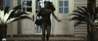 A Woman Is Running Out Of A House Carrying A Purse . GIF
