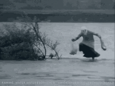 A Woman Is Running Through A River Carrying A Bag Of Food . GIF