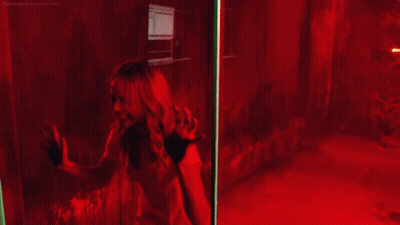 A Woman Is Screaming Behind A Glass Door With A Red Light Behind Her GIF