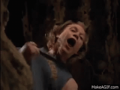A Woman Is Screaming In A Cave With Her Mouth Open While A Man Is Holding Her . GIF