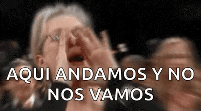 A Woman Is Screaming In A Crowd Of People While Covering Her Face . GIF