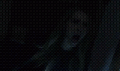 A Woman Is Screaming In A Dark Room With Her Mouth Wide Open . GIF