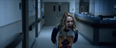 A Woman Is Screaming In A Hallway And Wearing A Shirt That Says Guns N Roses GIF