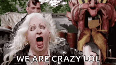 A Woman Is Screaming In Front Of A Carnival Ride While A Man Is Standing Behind Her . GIF