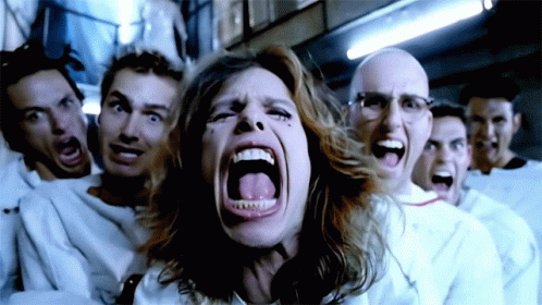A Woman Is Screaming In Front Of A Group Of Men In White Shirts GIF