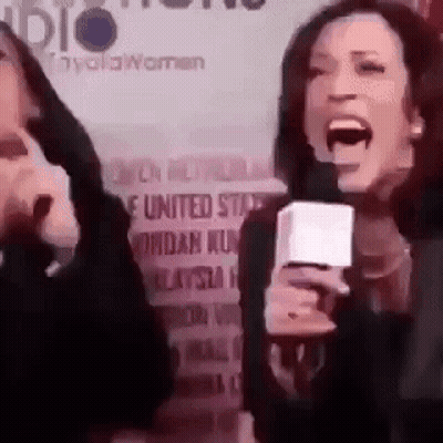 A Woman Is Screaming Into A Microphone While Another Woman Is Holding A Microphone . GIF