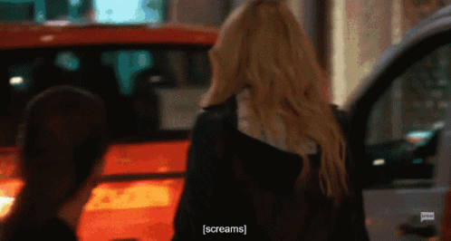 A Woman Is Screaming While Standing Next To A Car GIF