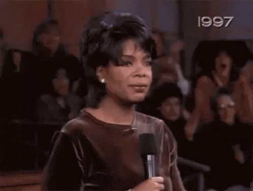 A Woman Is Screaming With Her Hands In The Air In A Crowd Of People . GIF