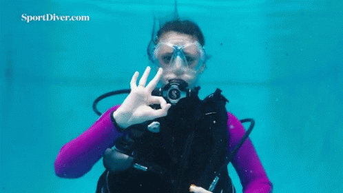 A Woman Is Scuba Diving In A Pool And Making An Ok Sign With Her Hand . GIF