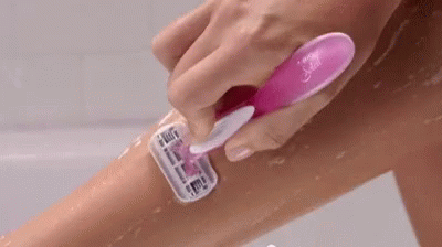 A Woman Is Shaving Her Leg With A Pink Razor In A Bathtub . GIF