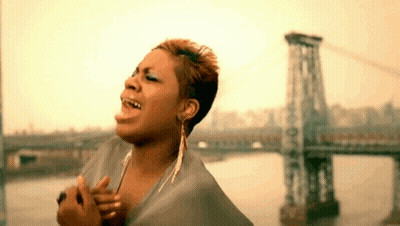 A Woman Is Singing In Front Of A Bridge In The Water . GIF
