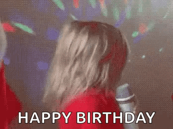 A Woman Is Singing Into A Microphone At A Birthday Party And Says `` Happy Birthday '' . GIF