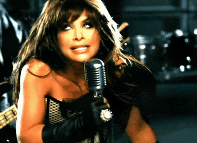 A Woman Is Singing Into A Microphone In A Dark Room GIF