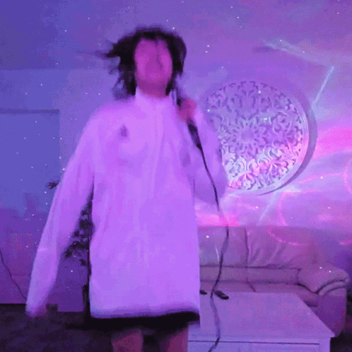 A Woman Is Singing Into A Microphone In Front Of A Purple Wall GIF