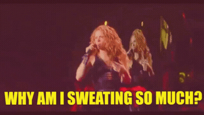 A Woman Is Singing Into A Microphone On A Stage And The Words `` Why Am I Sweating So Much '' Are Above Her . GIF