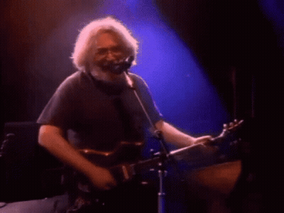 A Woman Is Singing Into A Microphone On A Stage In A Dark Room . GIF