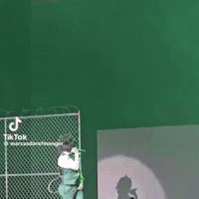 A Woman Is Singing Into A Microphone On A Stage While A Man Stands Behind Her . GIF