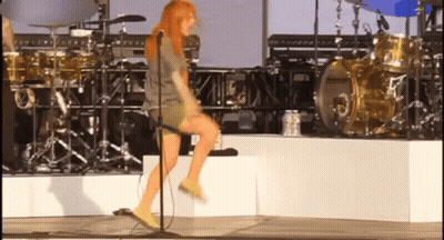 A Woman Is Singing Into A Microphone On Stage GIF