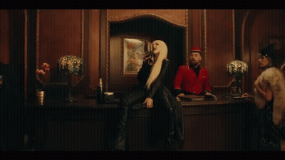 A Woman Is Singing Into A Microphone While Wearing A Black Jacket . GIF