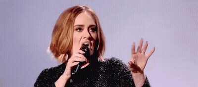 A Woman Is Singing Into A Microphone With Her Mouth Open . GIF
