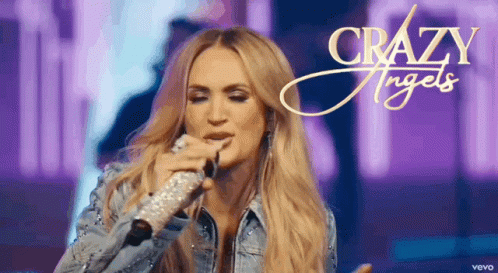 A Woman Is Singing Into A Microphone With The Words Crazy Angels Written On The Bottom GIF