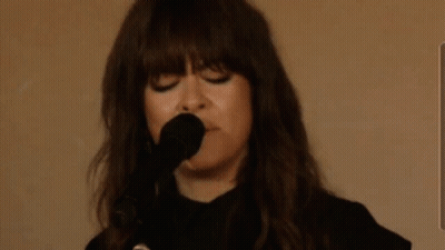 A Woman Is Singing Into A Microphone With The Words Sie7evec Written In The Background GIF