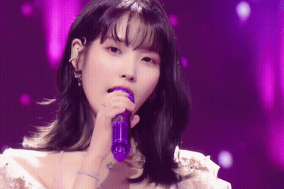 A Woman Is Singing Into A Purple Microphone . GIF