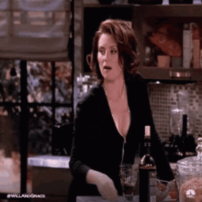 A Woman Is Sitting At A Counter In A Kitchen With A Bottle Of Wine And A Glass Of Wine . GIF
