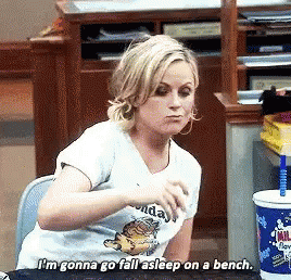 A Woman Is Sitting At A Desk And Says I 'M Gonna Go Fall Asleep On A Bench .. GIF