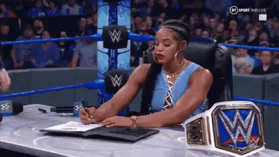 A Woman Is Sitting At A Desk In A Wrestling Ring Signing A Contract . GIF