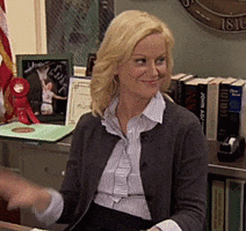 A Woman Is Sitting At A Desk In Front Of A Clock That Says 1816 GIF