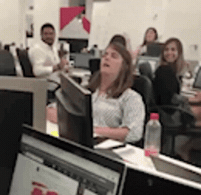 A Woman Is Sitting At A Desk In Front Of A Computer Monitor In An Office . GIF