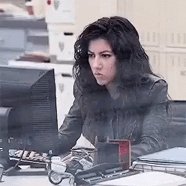 A Woman Is Sitting At A Desk In Front Of A Computer Screen . GIF